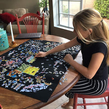Young girl working on a puzzle on top of the black felt mat.